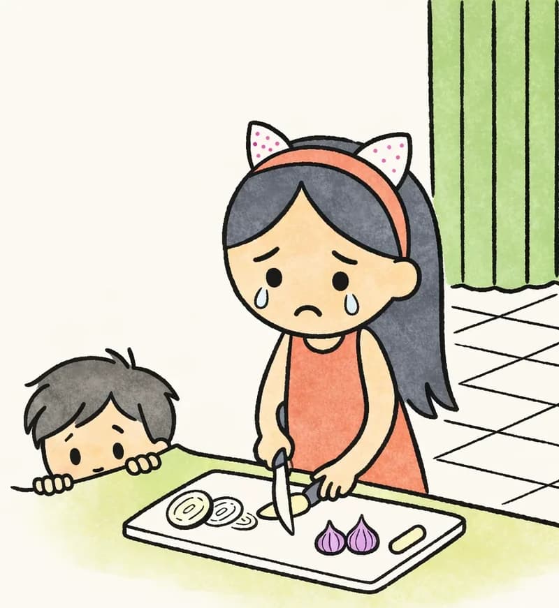 On the right side of the image, Little Brother peeks over the edge of a kitchen counter, with just his eyes and hands visible, looking up with a concerned, worried expression. He is watching Big Sis, who stands at the counter chopping onions on a cutting board — her eyes are teary and her expression looks sad. The scene is set indoors in a bright kitchen with tiled flooring and green curtains visible in the background. The left side of the image is plain white background.