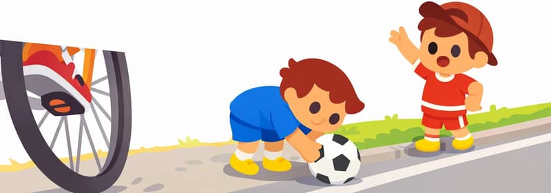 On the right side of the image, Fafa is bent over on the road reaching down to grab a soccer ball, head lowered and unaware of his surroundings, wearing a blue short-sleeved soccer jersey, blue shorts, white socks, and yellow cleats. Jojo stands further to the right at the roadside, one arm raised, calling out to Fafa with an alarmed expression, wearing a red short-sleeve shirt, red shorts with white horizontal stripes, a dark reddish-brown baseball cap worn backwards, white socks, and yellow shoes. A large bicycle wheel looms dramatically in the left-center foreground, speeding toward Fafa, conveying imminent danger. The scene is set on a suburban road with a narrow grass curb separating the sidewalk from the street, under bright daylight.