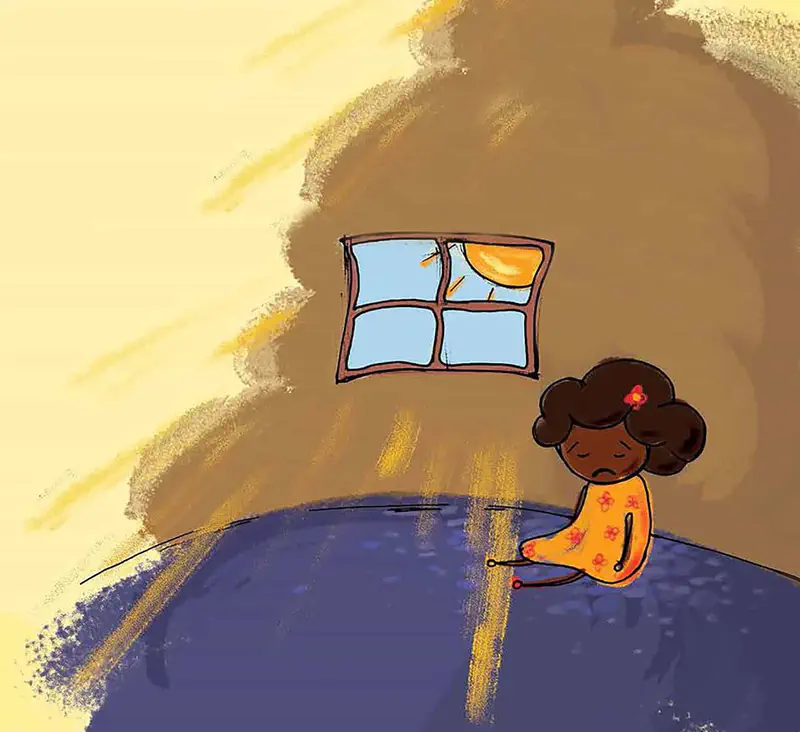 A sad girl with curly brown hair in an orange dress sits alone in a sunny room with light streaming through a window.