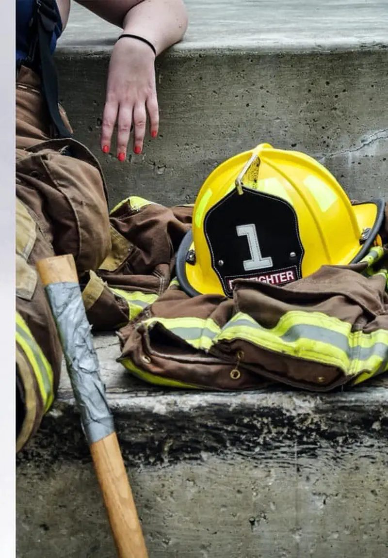 A yellow firefighter helmet with the number one rests on a brown firefighter jacket with reflective stripes and an axe.