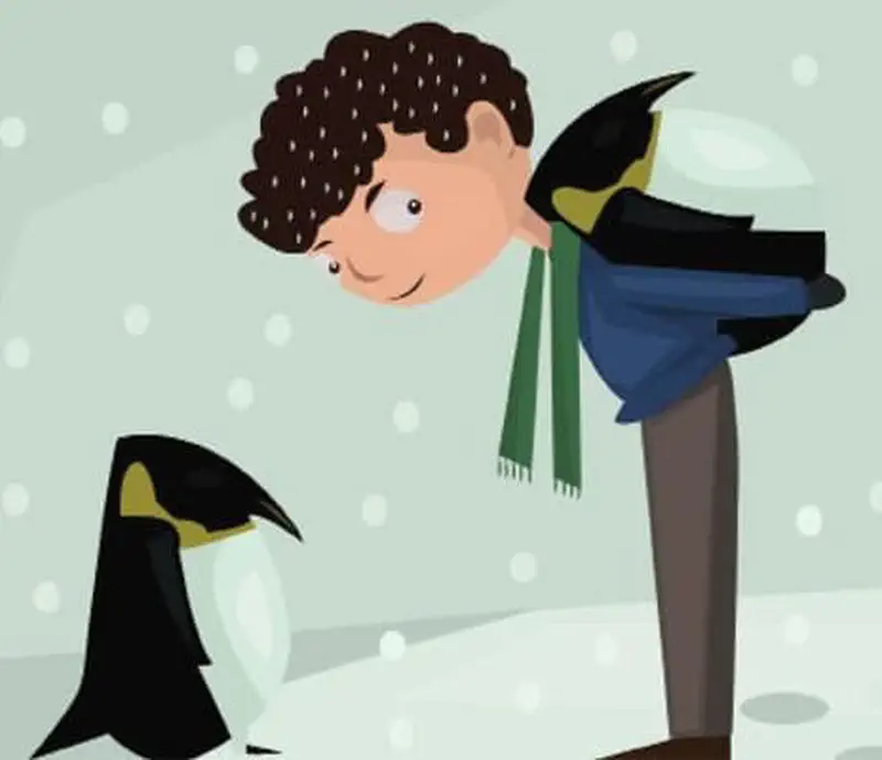 A boy with curly hair dressed as a penguin wearing a green scarf, standing in snow next to a real penguin while snowflakes fall.