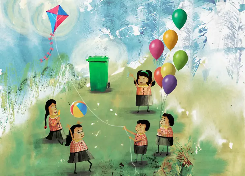 Children in school uniforms play with balloons, a kite, and a ball in a park with a green recycling bin nearby.