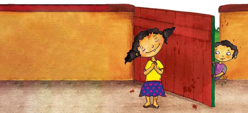 A proud girl with pigtails stands smiling in front of a red painted gate. A curious boy peeks from behind the gate.