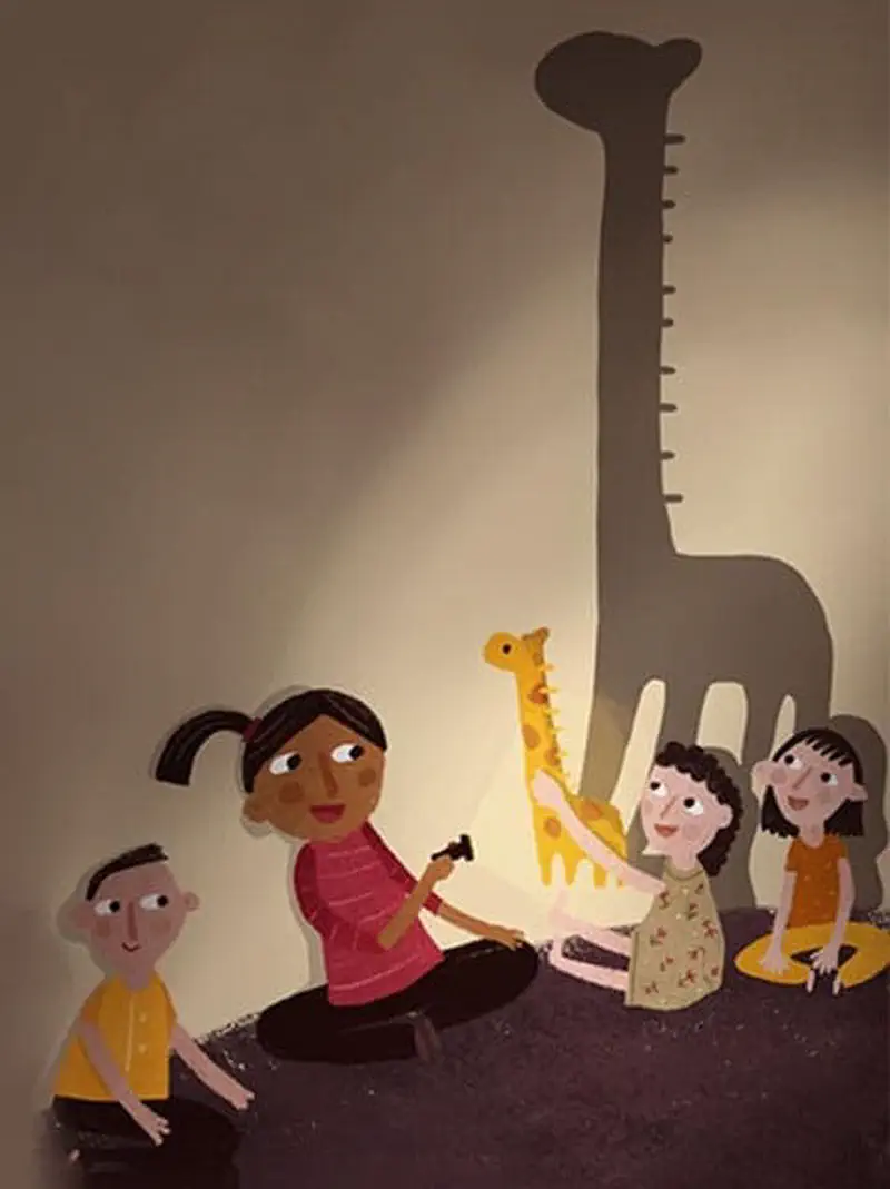 Girl with flashlight making giraffe shadow puppet on wall while children watch and smile.