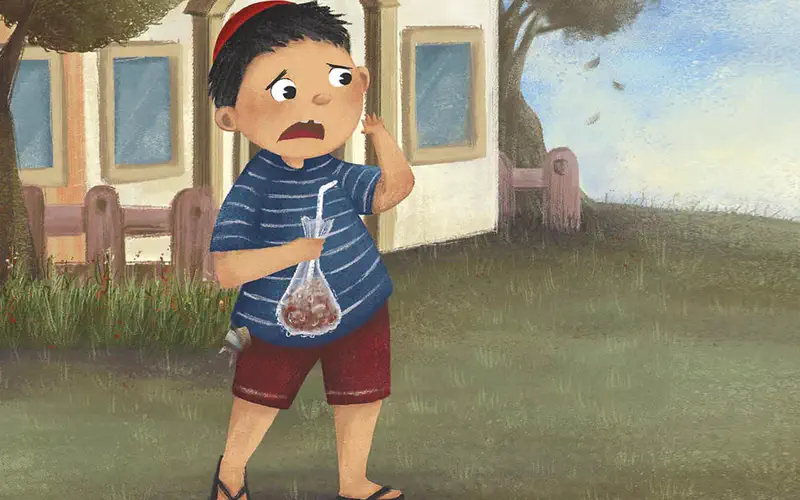 Worried boy with red cap holding plastic bag of food walking past fence near tree.