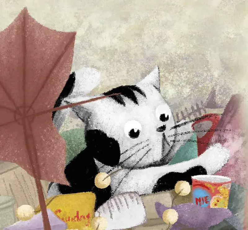 Black and white cat relaxing on pile of junk with noodle cup and umbrella nearby.