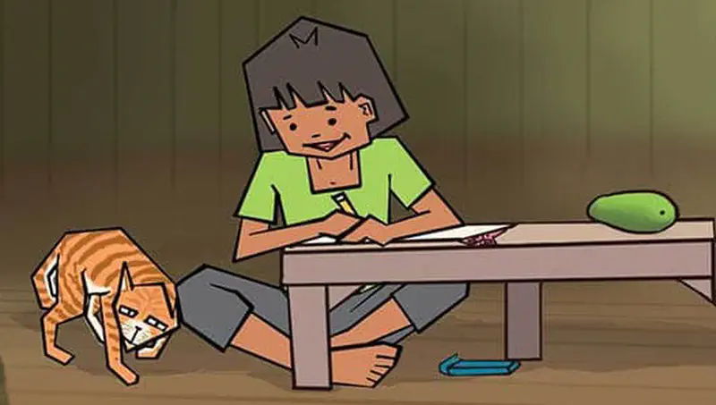 Boy sitting at low table drawing while orange striped cat walks under the table.