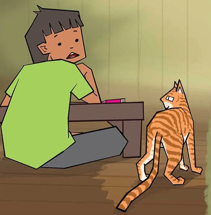 Boy looking surprised at orange striped cat walking away from him in wooden room.