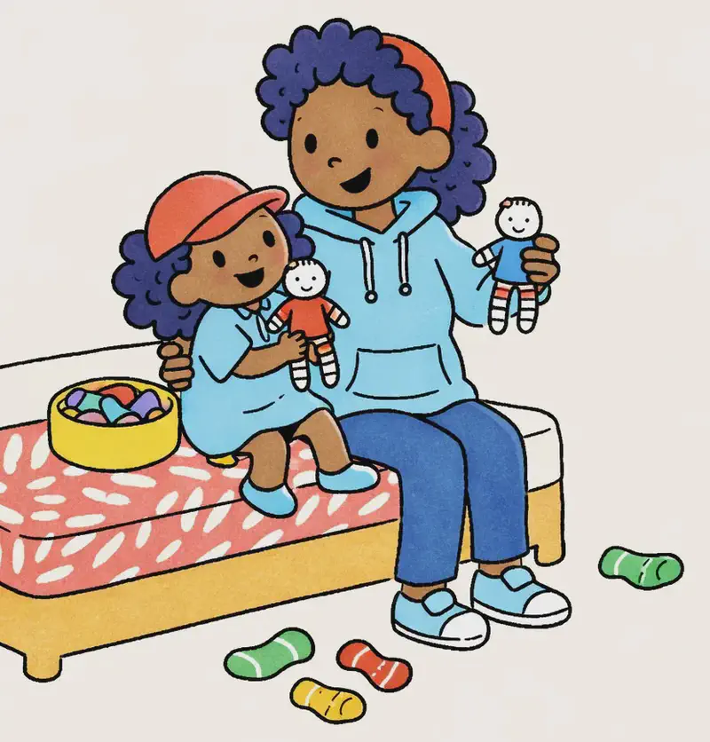 On the left side of the image, Mum and Alana sit together on a bed with a patterned red-and-white bedspread. Mum holds up a small completed sock doll, smiling contentedly, while Alana sits on her lap holding another finished sock doll, looking happy and engaged. Between them on the bed is a bowl filled with colourful materials for crafting. Several loose socks in various colours (green, yellow, red-striped) are scattered on the floor to the right of the bed. The scene is set indoors in a bright, cheerful bedroom.