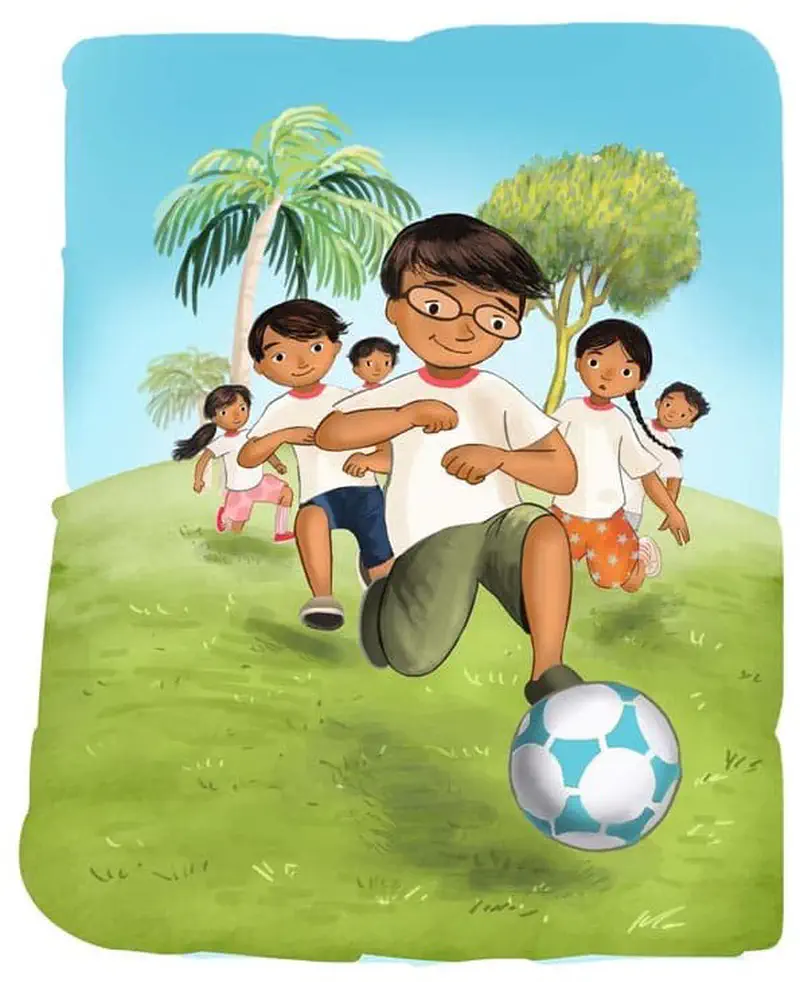 A boy with glasses in a white shirt dribbles a soccer ball while other children in white shirts run behind him on a grassy field with palm trees.