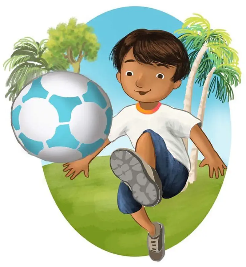 A boy in a white shirt and blue shorts kicks a large blue and white soccer ball toward the viewer with palm trees and green trees in the background.