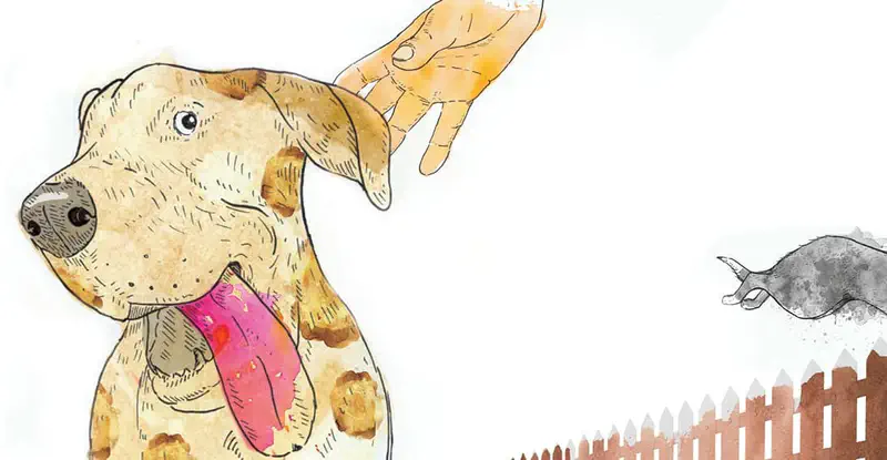 A happy tan spotted dog with tongue out gets petted while a gray dog jumps over a fence in the background.