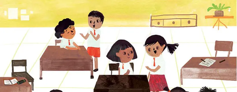 Four students in white shirts and red skirts chat excitedly in a classroom with wooden desks and yellow walls.