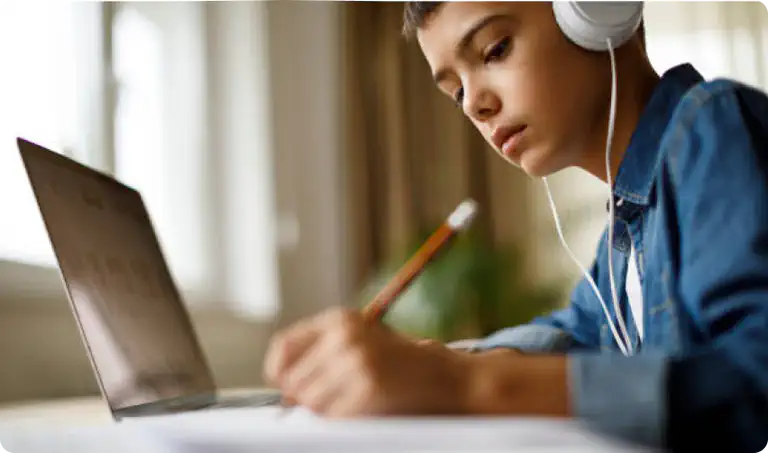 a photo of a boy wearing headphones and using a laptop